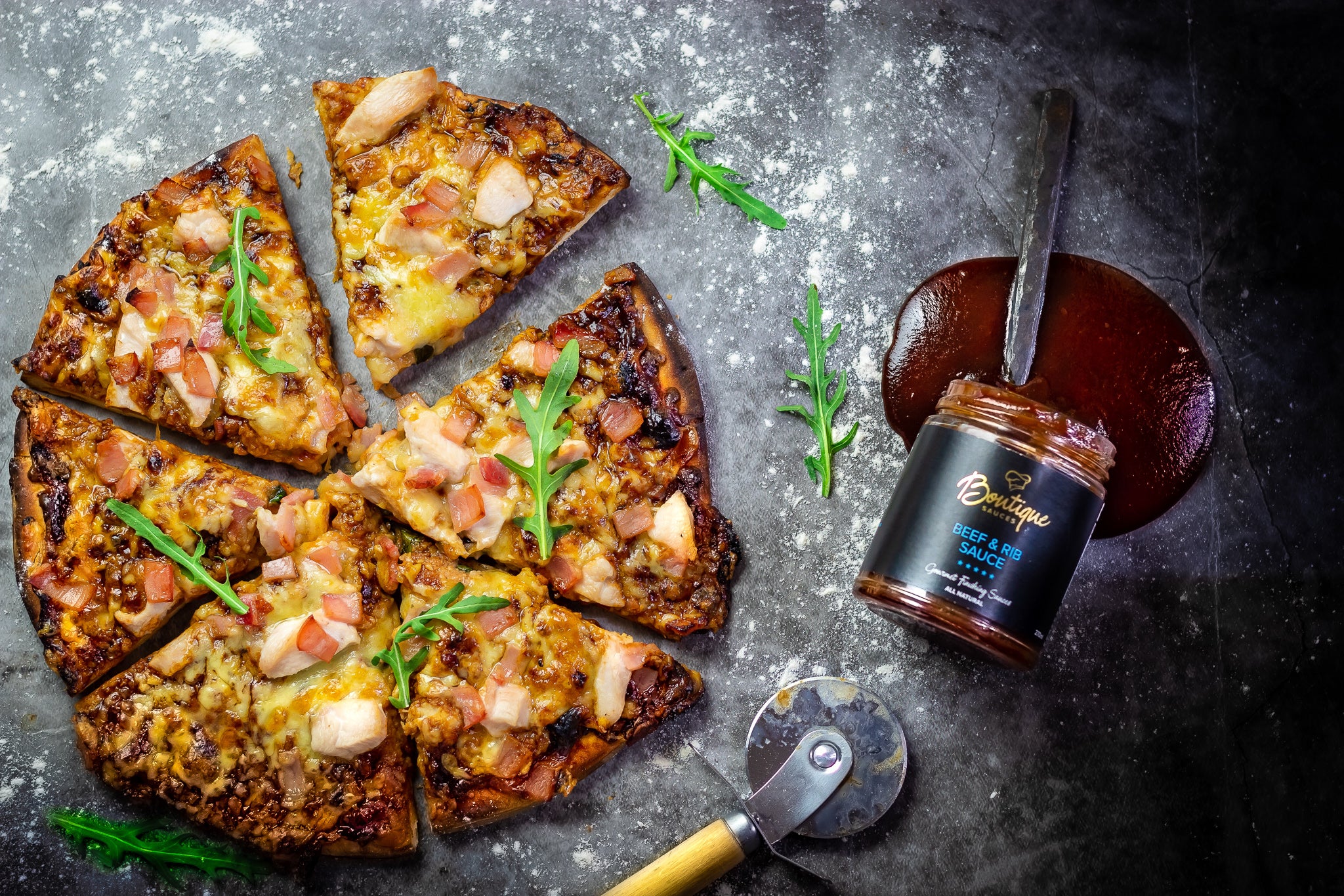 Smoky BBQ pizza topped with chicken, bacon, salami, and fresh rocket, made with Boutique Sauces Beef & Rib Sauce as the base. A bold, flavorful twist on pizza night