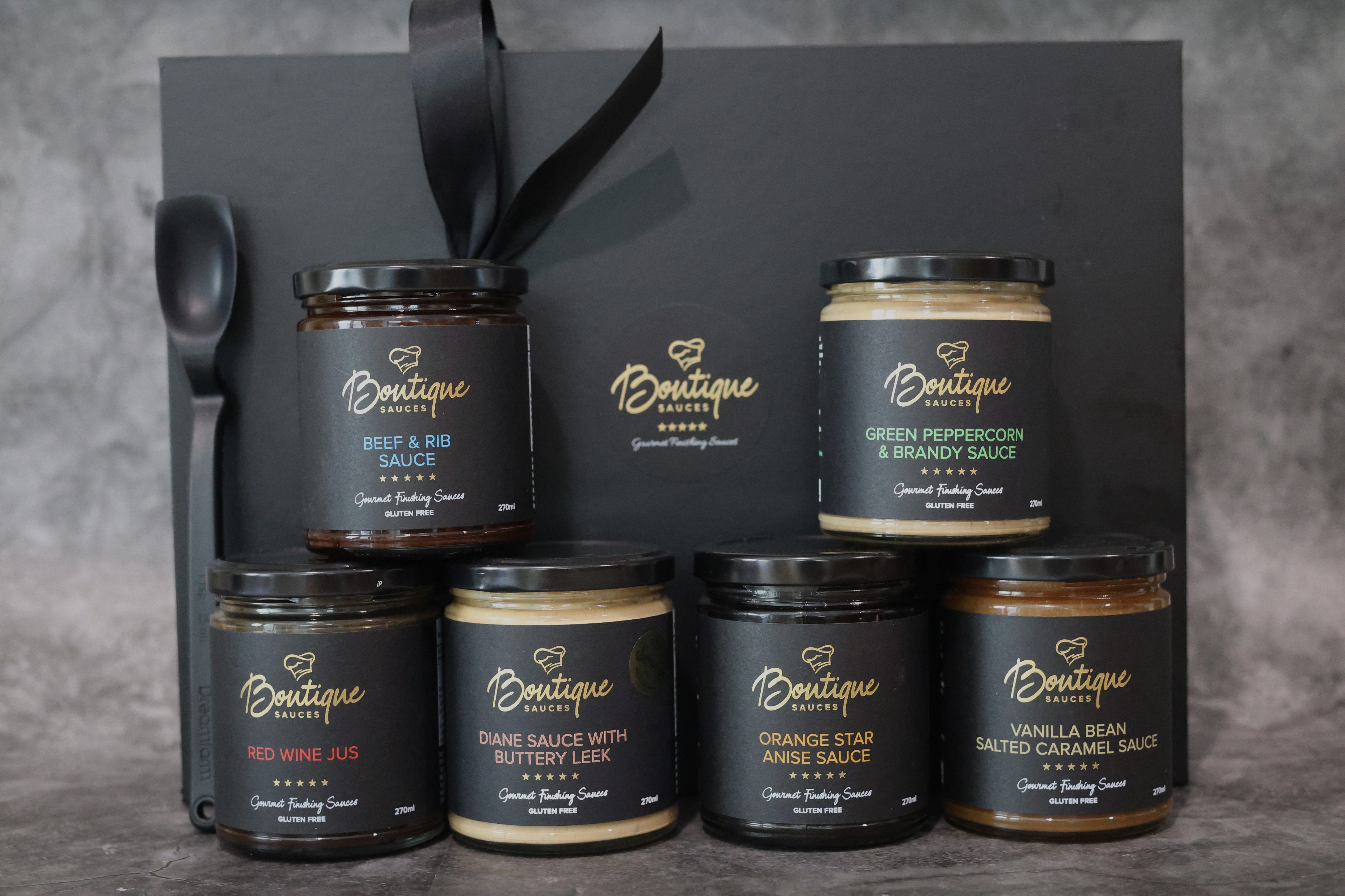 Gourmet sauce gift set by Boutique Sauces featuring Beef & Rib Sauce, Red Wine Jus, Diane Sauce with Buttery Leek, Green Peppercorn & Brandy Sauce, Orange Star Anise Sauce, and Vanilla Bean Salted Caramel Sauce. The perfect foodie gift for home cooks and entertainers