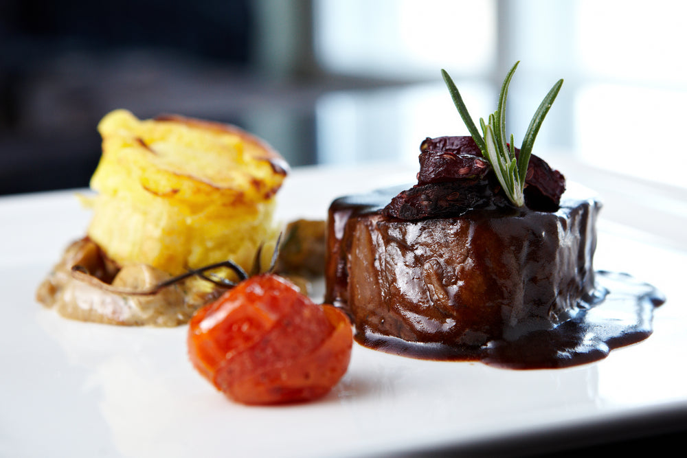 Perfectly cooked beef fillet with a rich red wine jus, served with dauphinoise potatoes and roasted tomato. A gourmet dish featuring Boutique Sauces Red Wine Jus
